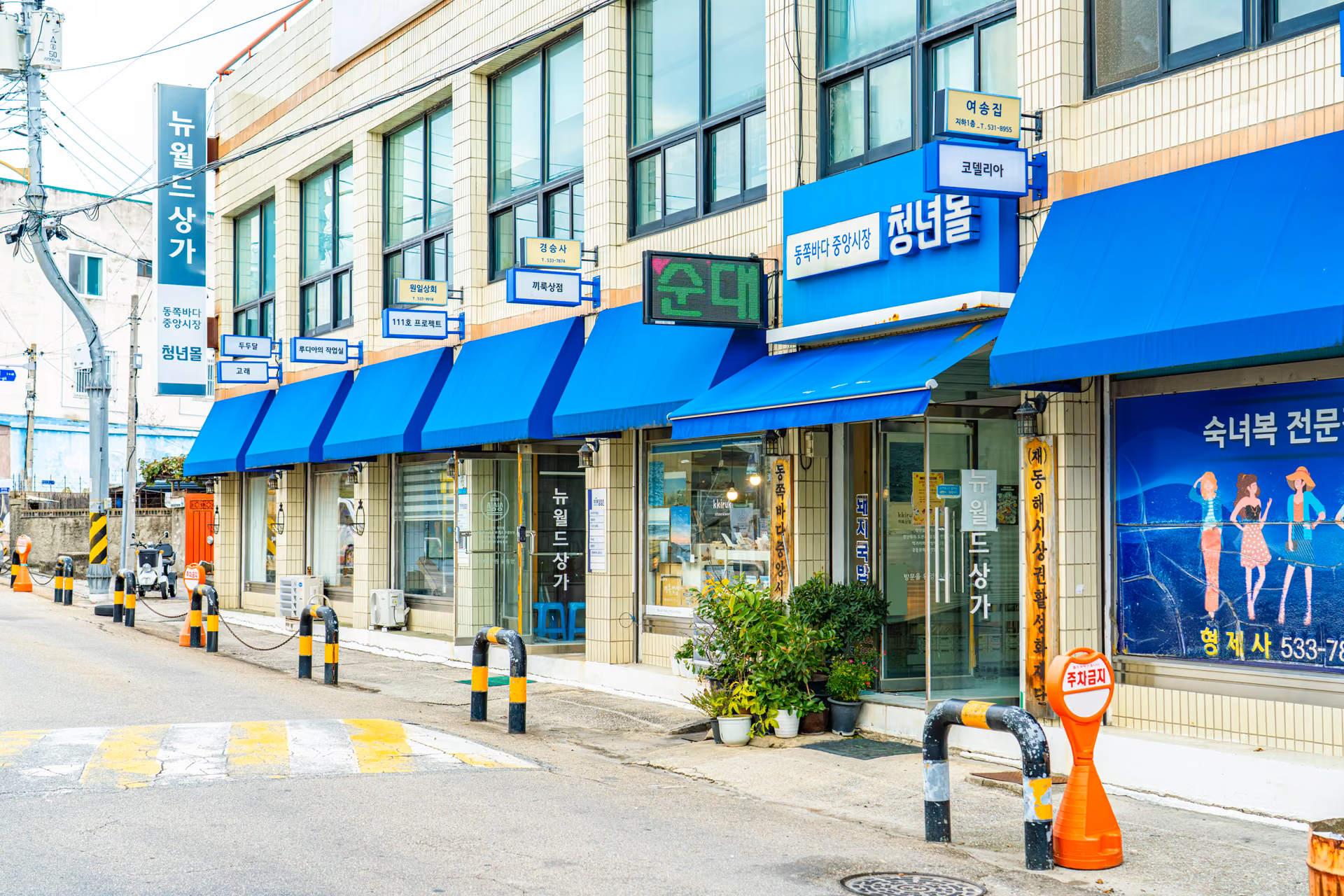 파란 차양이 달린 뉴월드상가 건물과 청년몰 간판